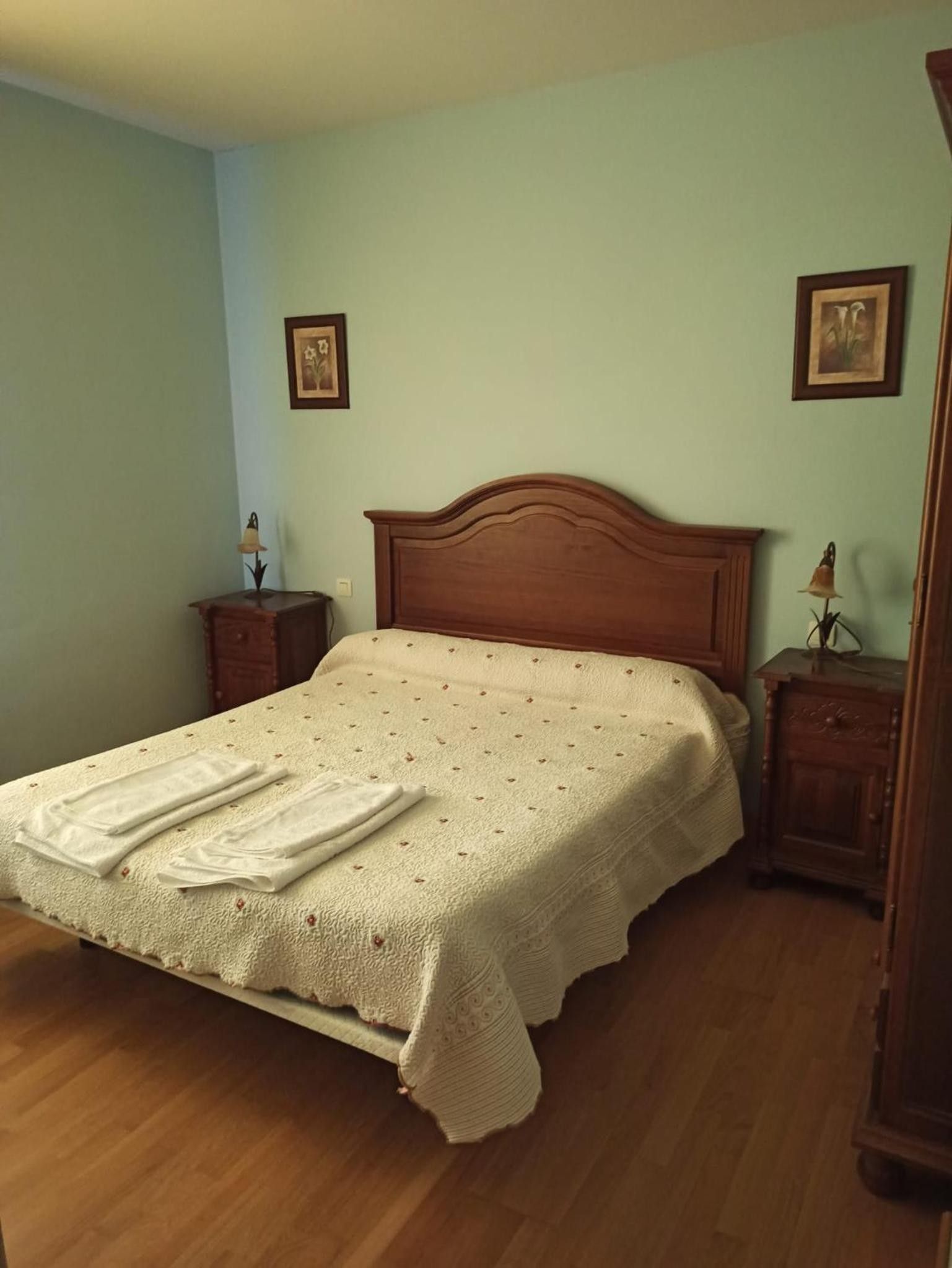 A bedroom with a wooden bed, a nightstand, and a dresser.