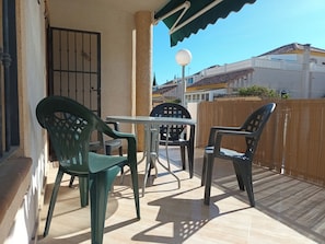 An outdoor patio with a table and chairs, a tiled floor, and a view of buildings in the background. - House Sleeps 4 - Air Con, Parking, Community Pool (San Fulgencio)