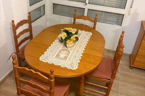 A round wooden dining table with a lace tablecloth, surrounded by wooden chairs with cushioned seats. - House Sleeps 4 - Air Con, Parking, Community Pool (San Fulgencio)