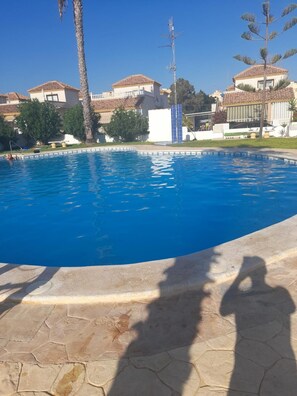 A swimming pool with a clear blue water surface, surrounded by a stone deck. - House Sleeps 4 - Air Con, Parking, Community Pool (San Fulgencio)