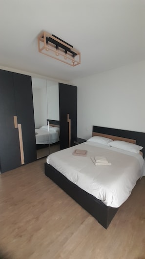 Quarto moderno com uma cama grande, um guarda-roupa e um espelho.