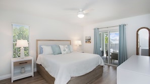 A bedroom with a bed, bedside tables, a ceiling fan, and a view through a glass door. - Lovely 3-bedroom house on canal with pool Marco Island (Marco Island)