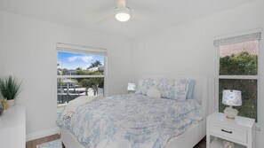 A bedroom with a bed, bedside table, lamp, and a view of a marina. - Lovely 3-bedroom house on canal with pool Marco Island (Marco Island)