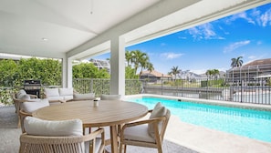 A covered outdoor area with a pool, seating, and a grill. - Lovely 3-bedroom house on canal with pool Marco Island (Marco Island)