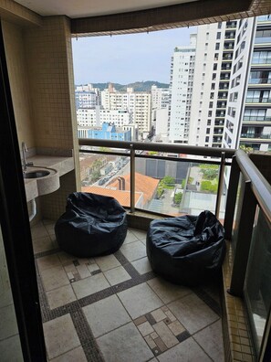 A balcony with a view of a cityscape, a sink, and two bean bags. - 3-bedroom apartment with ocean view and 2 covered parking spaces. (Florianópolis)