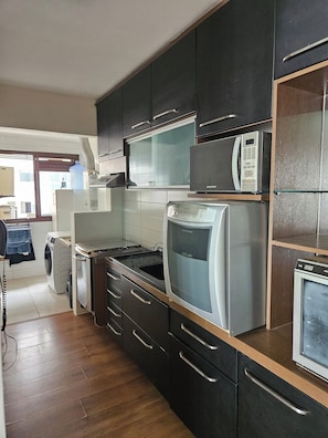 A modern kitchen with stainless steel appliances, wooden cabinets, and a built-in microwave. - 3-bedroom apartment with ocean view and 2 covered parking spaces. (Florianópolis)