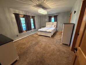 Ein Schlafzimmer mit einem Bett, einem Nachttisch, einer Kommode und einer Deckenleuchte.