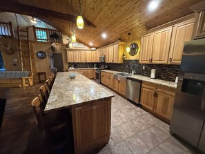 A spacious kitchen with wooden cabinets, a granite countertop, and modern appliances.