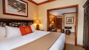 Een hotelkamer met een groot bed, een houten hoofdbord, een rood kussen, een lamp en een schilderij aan de muur.
