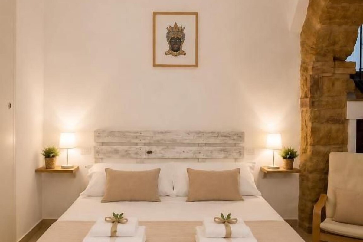 A neatly made bed with a headboard, two bedside tables with lamps, and a framed picture on the wall.
