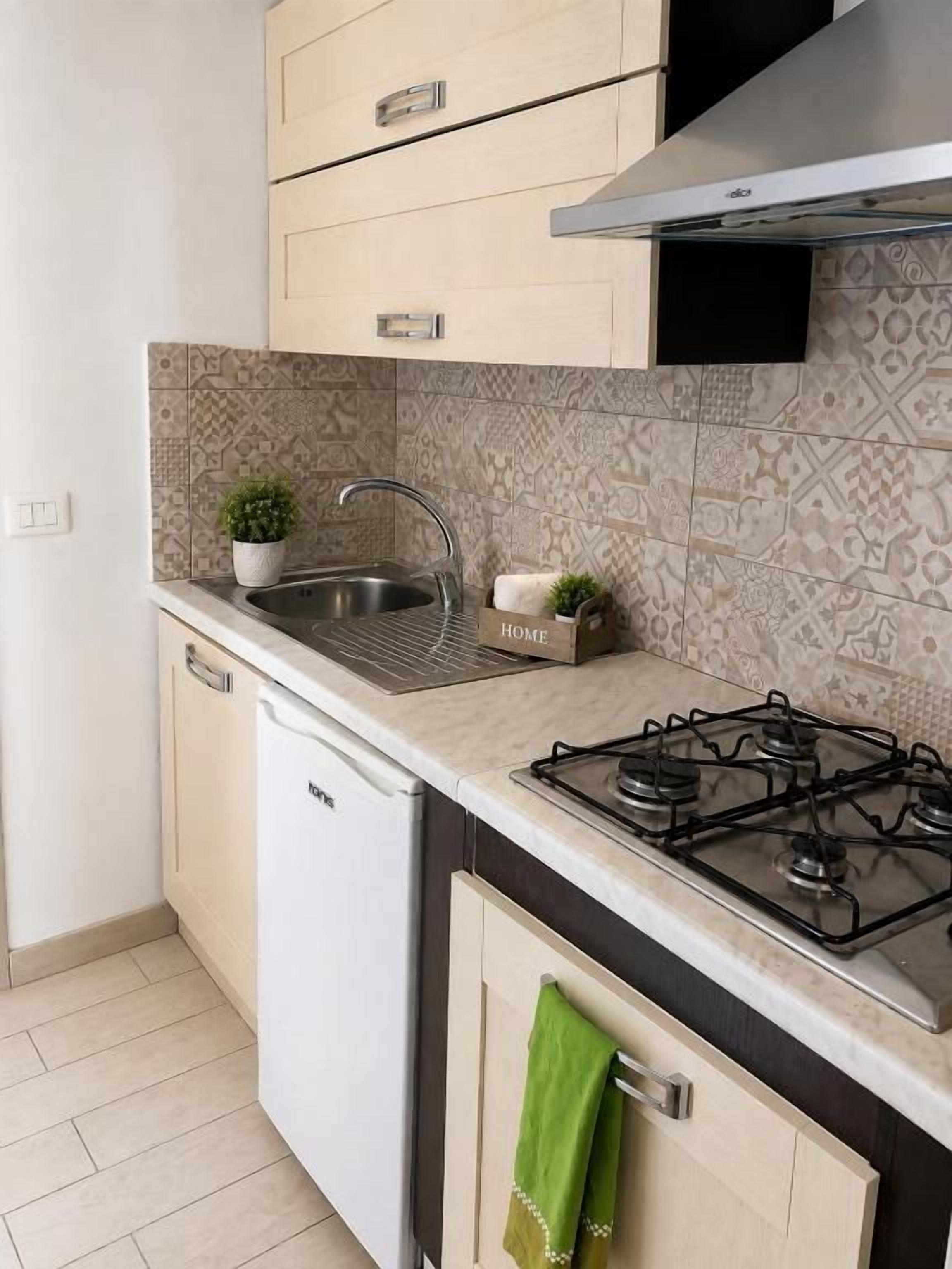 A compact kitchen with a built-in dishwasher, a gas stove, and a patterned backsplash.