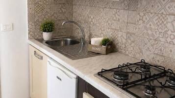 A compact kitchen with a built-in dishwasher, a gas stove, and a patterned backsplash.