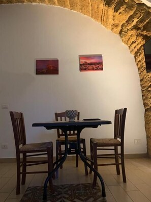 A dining area with a table and chairs, a patterned rug, and two paintings on the wall.