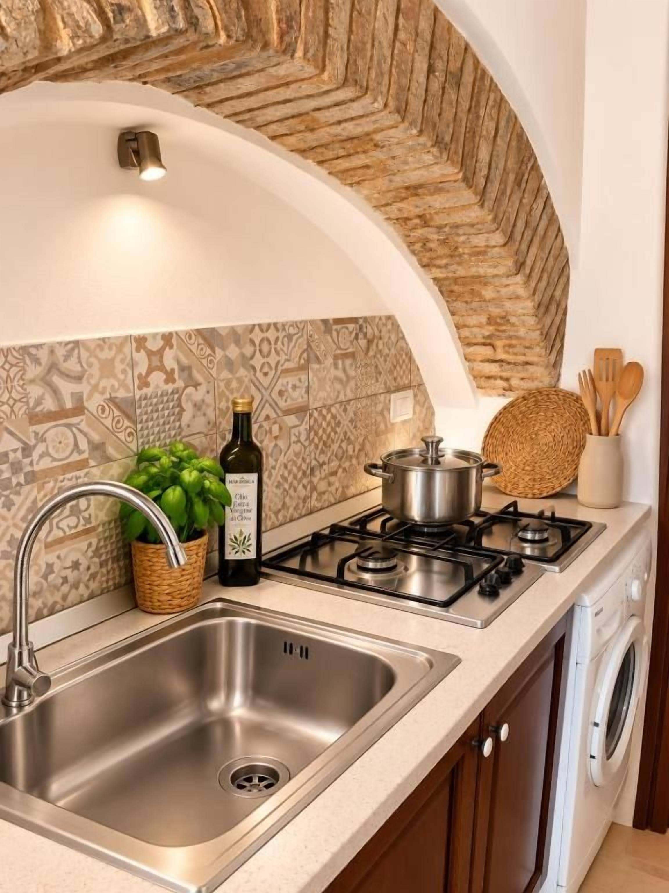 Une cuisine équipée d’un évier en acier inoxydable, d’une cuisinière à gaz et d’un lave-linge.