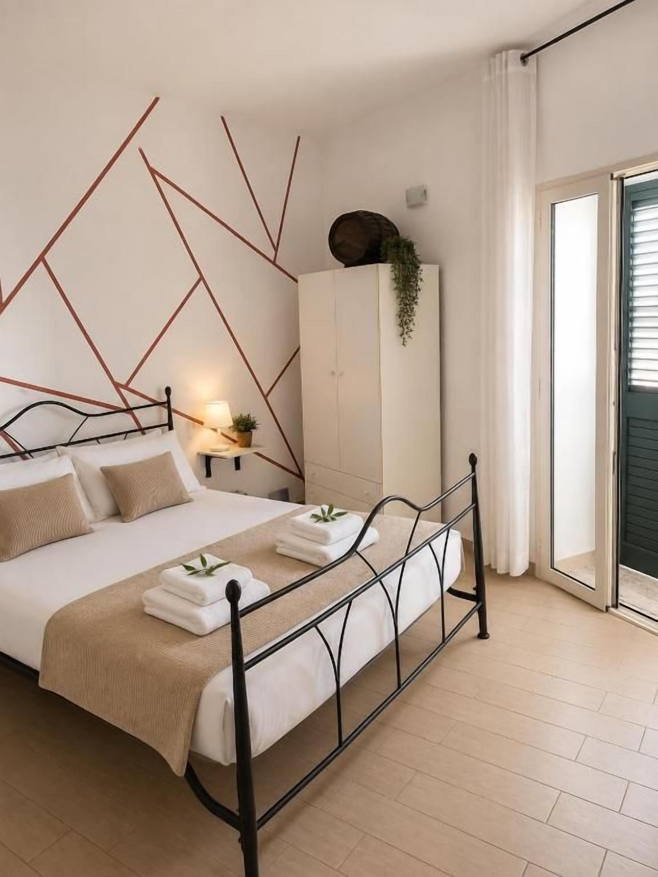 A bedroom with a bed, bedside table, and a view of the outside.