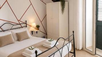 A bedroom with a bed, bedside table, and a view of the outside.