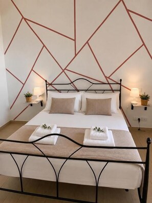 A bed with a geometric wall design, two bedside lamps, and a metal frame. - TELAMON HOME RENT (Agrigento)