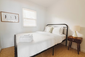 A neatly made bed with white linens, a bedside lamp, and a framed picture on the wall. - The Lazy Days Main Cottage - Lakefront (Lambton Shores)