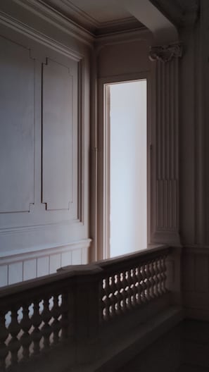 A room with a large window, a white door, and a dark wooden railing. - Hotel walburga (Bruges)