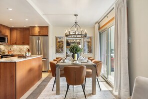 A modern kitchen with stainless steel appliances, a dining area with a large table and chairs, and a view through a glass door. - Modern Western Luxury in Lionshead, 2min walk to Gondola, Hot Tubs & Ski Locker (Vail)