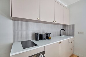 A modern kitchen with a white countertop, a built-in stove, a sink, and a coffee maker. - Charming 2BDR AC Le Marais Centre de Paris (Paris)