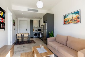 A modern living room with a sofa, a coffee table, and a dining area with chairs. - 1 bedroom in Punta Cana with pool and gym (Punta Cana)