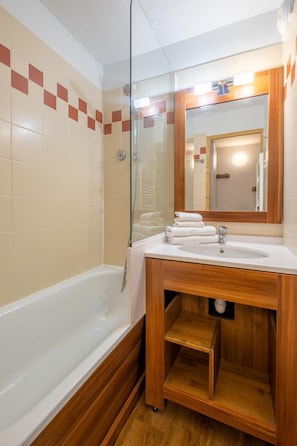 A bathroom with a bathtub, a sink, and a mirror. - Wifi, 10m from ski slopes, sauna, hammam, ski locker, 28-30m², Val Thorens (Val Thorens)