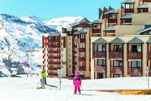 A ski resort with multi-story buildings, ski slopes, and snow-covered mountains in the background. - Wifi, 10m from ski slopes, sauna, hammam, ski locker, 28-30m², Val Thorens (Val Thorens)