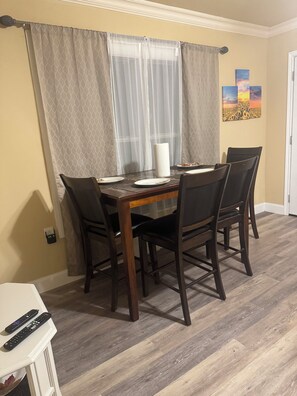 A dining area with a wooden table, four chairs, a white tablecloth, and a wall-mounted painting. - Cozy 2-bedroom duplex in awesome Dallas and close to downtown Dallas (Dallas)