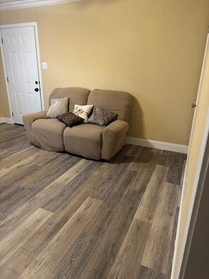 A beige wall, a brown sofa with patterned cushions, and a wooden floor. - Cozy 2-bedroom duplex in awesome Dallas and close to downtown Dallas (Dallas)