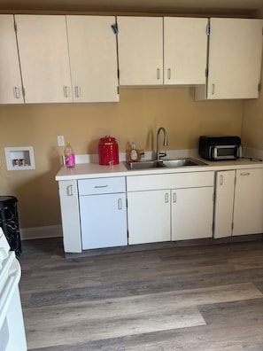 A kitchen with white cabinets, a stainless steel sink, a toaster, and a red container. - Cozy 2-bedroom duplex in awesome Dallas and close to downtown Dallas (Dallas)