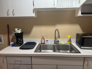 A kitchen with a double sink, a coffee maker, a dish soap bottle, a sponge, and a microwave. - Cozy 2-bedroom duplex in awesome Dallas and close to downtown Dallas (Dallas)
