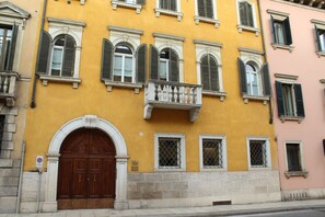 A yellow building with a large wooden door, multiple windows with shutters, and a balcony with a balustrade. - Lovely Stay in Verona N.2 (Verona)