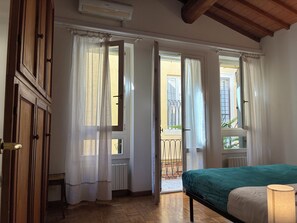 A bedroom with a bed, a bedside lamp, and a view of the outside balcony. - Lovely Stay in Verona N.2 (Verona)