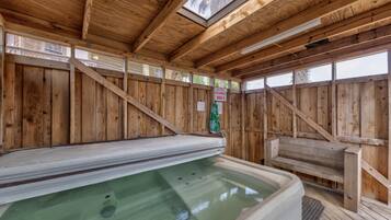 Un espace de détente en bois comprenant un jacuzzi, des murs en bois et une verrière.