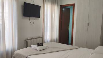 A hotel room with a bed, a TV mounted on the wall, a wardrobe, and a door.