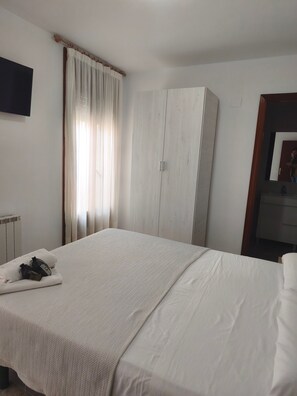 Een slaapkamer met een bed, een kledingkast, een radiator en een raam met gordijnen.