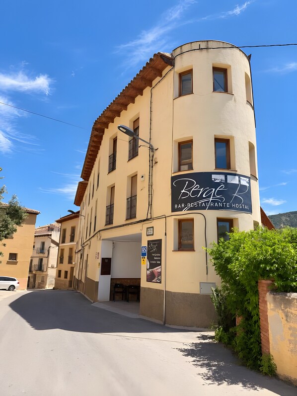Un edificio con un'insegna che indica 'Berge Bar-Bistro Hostal', suggerendo che si tratti di un ristorante e un ostello.