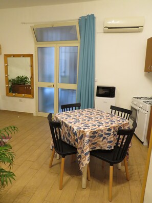 A dining area with a table set for four, a microwave, a stove, a cabinet, a mirror, and a window with curtains. - Essential and central apartment (Palermo)