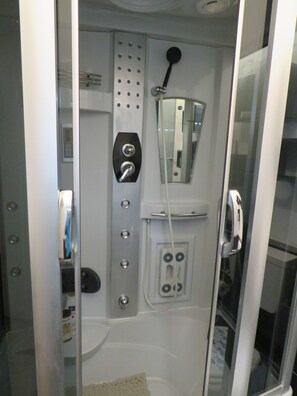 A bathroom with a glass door, a shower with a handheld showerhead, a towel rack, and a toilet. - Essential and central apartment (Palermo)