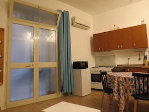 A compact kitchen with a refrigerator, microwave, stove, and a dining table with chairs. - Essential and central apartment (Palermo)