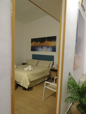 A bedroom with a bed, bedside tables, a mirror, and a painting on the wall. - Essential and central apartment (Palermo)
