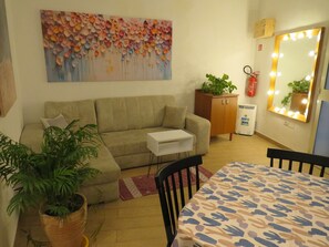 A living room with a sofa, a small table, a potted plant, a cabinet, and a mirror with lights. - Essential and central apartment (Palermo)