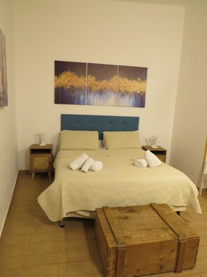 A bedroom with a bed, a nightstand, a wooden bench, and a painting on the wall. - Essential and central apartment (Palermo)