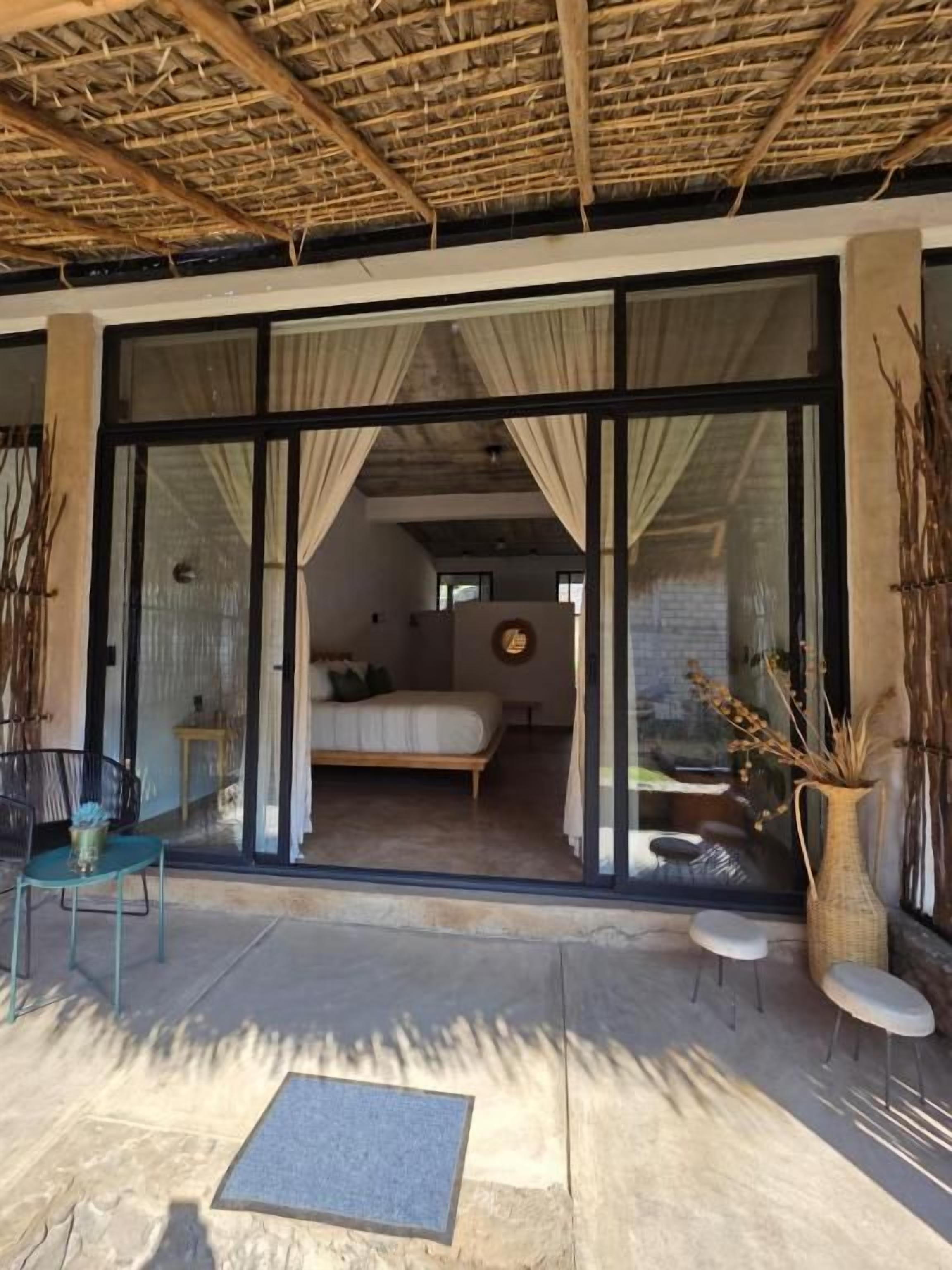 A room with a bed, a window, and a door leading to an outdoor area with a table and chairs.