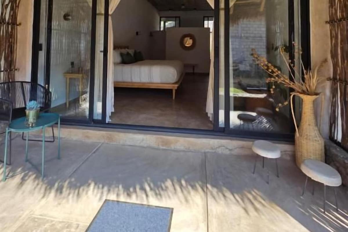 A room with a bed, a window, and a door leading to an outdoor area with a table and chairs.