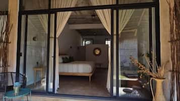 A room with a bed, a window, and a door leading to an outdoor area with a table and chairs.