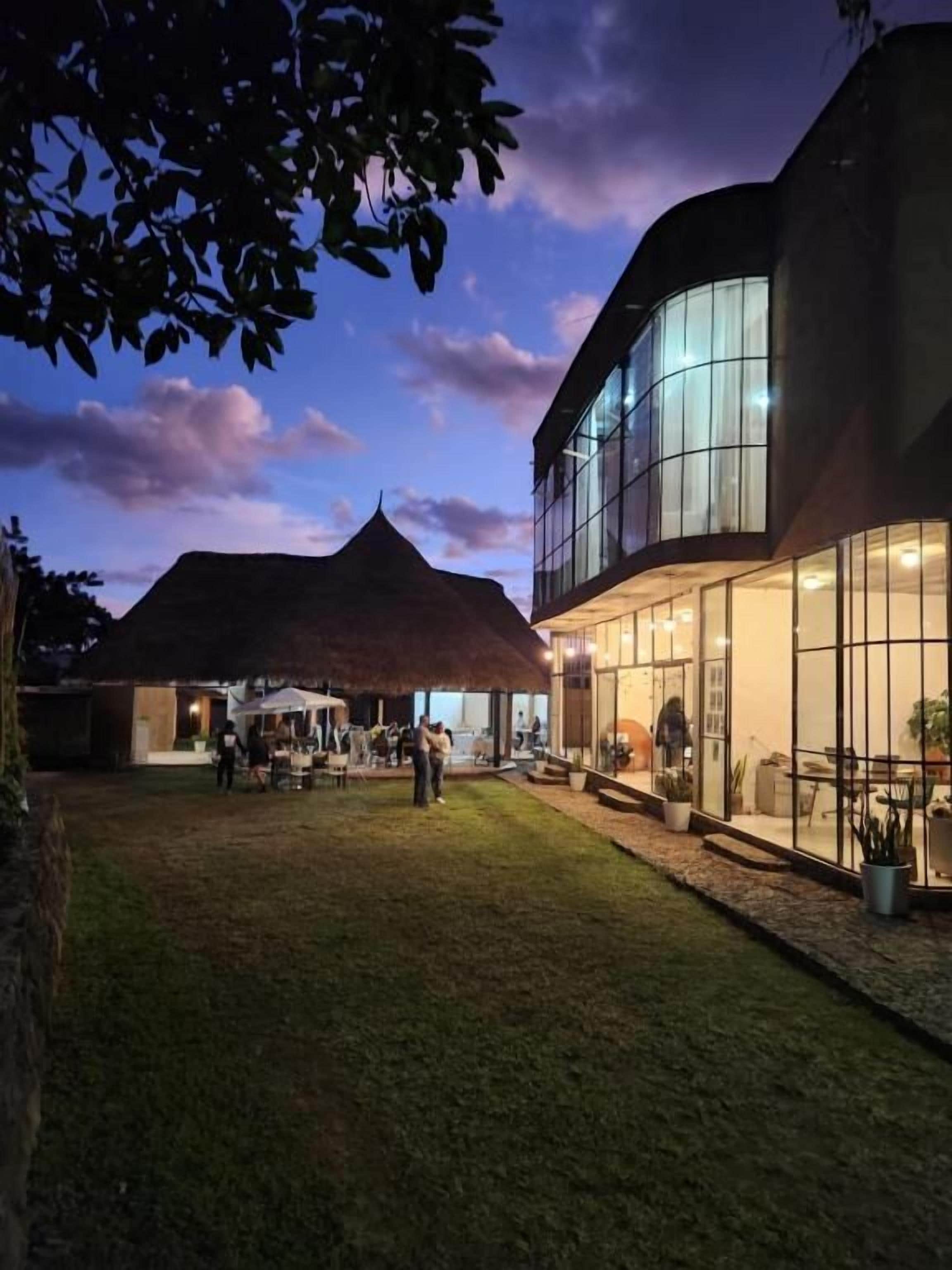 A building with a modern design, featuring large glass windows and a well-maintained lawn area.