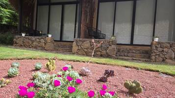 A building with a thatched roof, stone walls, and a garden with various plants and flowers.