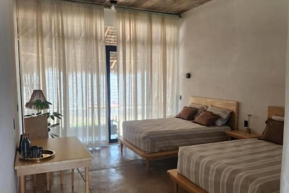 A room with two beds, a small table, and a ceiling fan.
